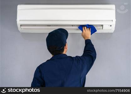 technician service cleaning the air conditioner with cloth