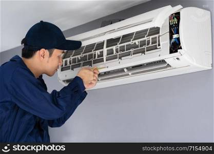 Technician service using screwdriver to repairing air conditioner indoors