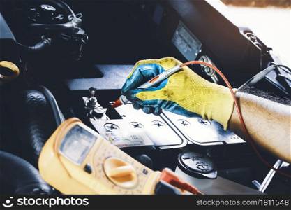 Technician to checking voltage stable of the car battery with digital multimeter probe