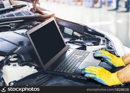 Technician tuning engine car with the computer laptop in repair garage,blank display