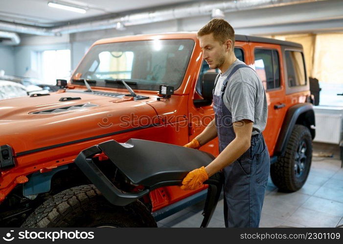 Technician working on auto tuning holding car arche before installation. Garage workshop. Technician working on car tuning in garage