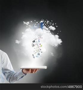 Technologies in use. Close up of hand holding tablet pc and icons flying in air