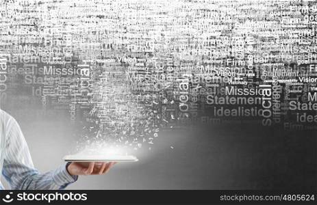 Technologies in use. Close up of hand holding tablet pc and words in air