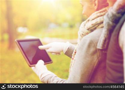 technology, advertisement and people concept - close up of couple hands in autumn gloves holding tablet pc computer outdoors