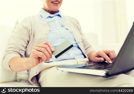 technology, age and people concept - close up of happy senior woman with laptop compute and credit or bank card r at home