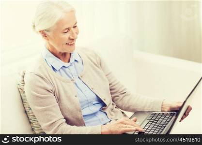 technology, age and people concept - happy senior woman with laptop computer at home
