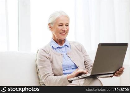 technology, age and people concept - happy senior woman with laptop computer at home
