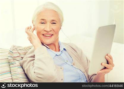 technology, age and people concept - happy senior woman with tablet pc computer and earphones listening to music at home