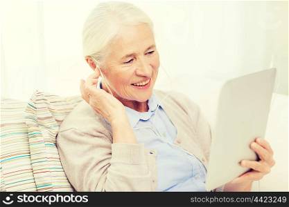 technology, age and people concept - happy senior woman with tablet pc computer and earphones listening to music at home