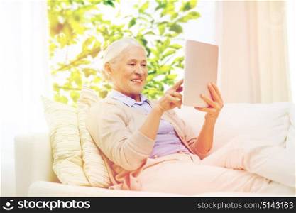 technology, age and people concept - happy senior woman with tablet pc computer at home over window and green natural background. happy senior woman with tablet pc at home