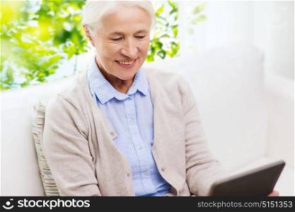 technology, age and people concept - happy senior woman with tablet pc computer at home over green natural background. happy senior woman with tablet pc at home