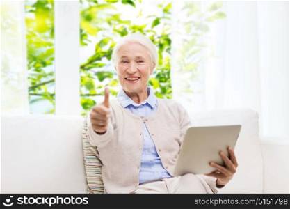 technology, age and people concept - happy senior woman with tablet pc computer showing thumbs up at home over window and green natural background. senior woman with tablet pc showing thumbs up