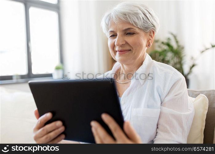 technology, age and people concept - happy senior woman with tablet pc computer at home. happy senior woman with tablet pc at home