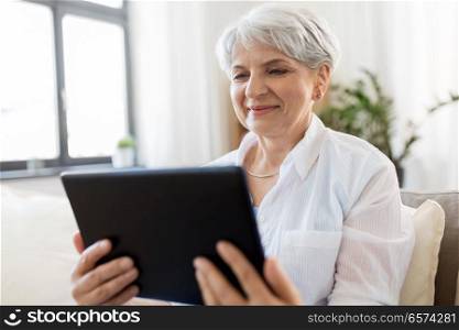 technology, age and people concept - happy senior woman with tablet pc computer at home. happy senior woman with tablet pc at home