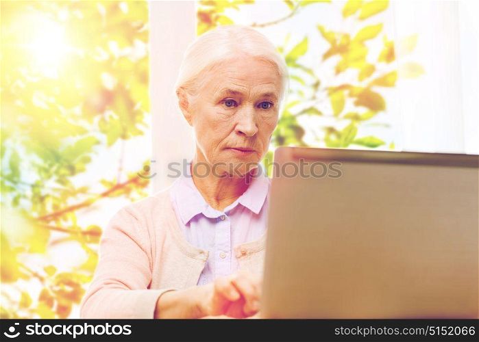 technology, age and people concept - senior woman with laptop computer at home over green natural background. senior woman with laptop at home