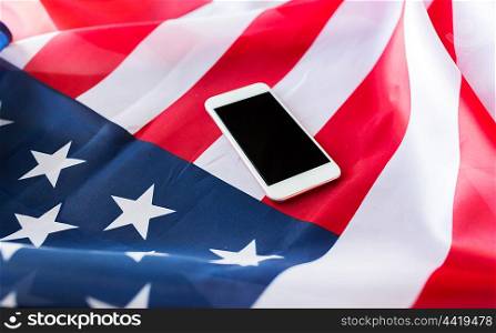 technology, american independence day, patriotism and nationalism concept - close up of smartphone with black blank screen on american flag