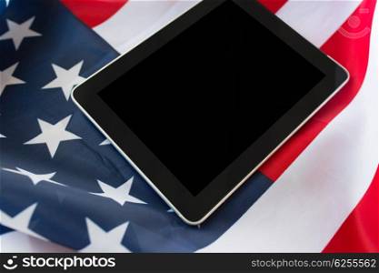 technology, american independence day, patriotism and nationalism concept - close up of tablet pc computer on american flag