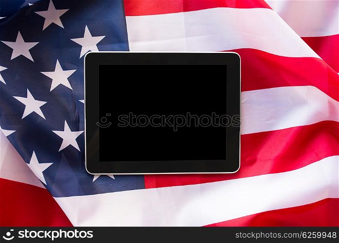 technology, american independence day, patriotism and nationalism concept - close up of tablet pc computer on american flag