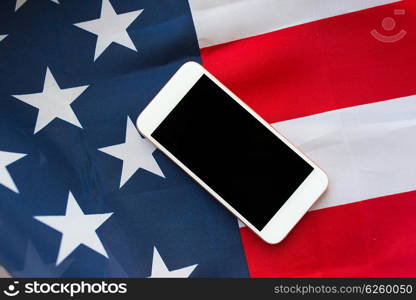 technology, american independence day, patriotism and nationalism concept - close up of smartphone computer on american flag