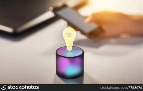 technology and ai concept - glowing smart speaker with virtual light bulb icon on table at office and virtual hologram of light bulb. smart speaker and virtual hologram of light bulb