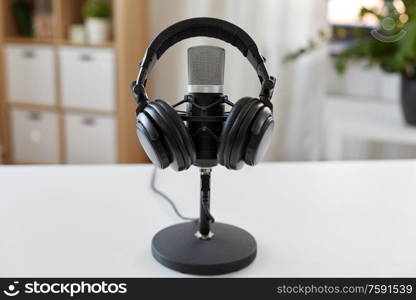 technology and audio equipment concept - headphones and microphone at home office or recording studio. headphones and microphone at home office