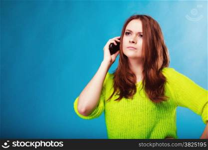Technology and communication. Amazed woman teenage girl talking on mobile phone, using smartphone on blue