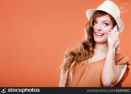 Technology and communication. Attractive summer woman talking on mobile phone orange background