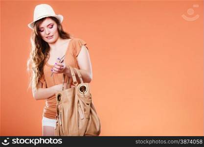 Technology and communication. Attractive summer woman using mobile phone holding handbag orange background