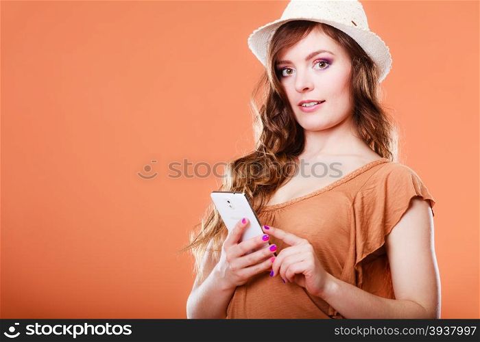 Technology and communication. Attractive summer woman using mobile phone texting on smartphone orange background