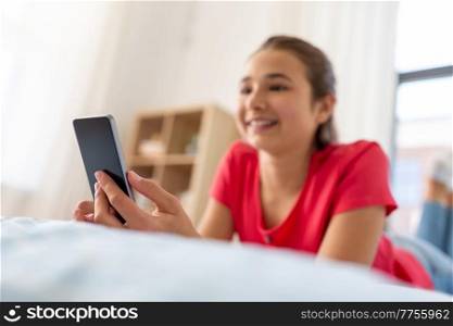 technology and communication concept - close up of smiling teenage girl texting on smartphone at home. smiling teenage girl texting on smartphone at home