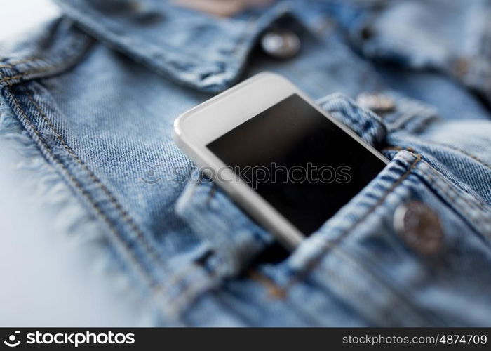 technology and communication concept - smartphone in pocket of denim jacket or waistcoat. smartphone in pocket of denim jacket or waistcoat