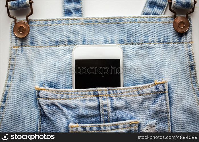 technology and communication concept - smartphone in pocket of denim overalls. smartphone in pocket of denim overalls