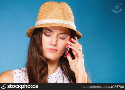 Technology and communication - confused teen girl talking on mobile phone smartphone, worried woman using cell phone on blue. Misunderstanding.