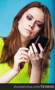 Technology and communication. Confused woman teenage girl texting on mobile phone, using smartphone reading sms message on blue
