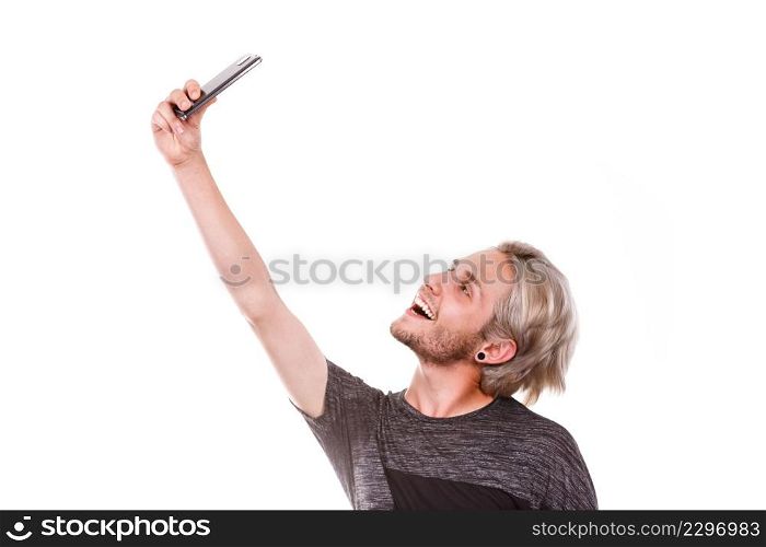 Technology and communication. Handsome young man stylish joyful guy taking self picture with mobile phone, isolated on white. Young man taking selfie photo with smartphone camera