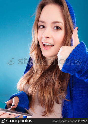 Technology and communication. Happy smiling woman teenage girl texting on mobile phone, using smartphone reading sms message making thumb up hand sign gesture on blue