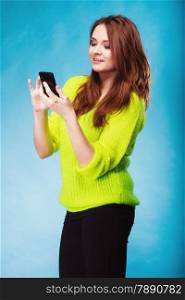 Technology and communication. Happy woman teenage girl texting on mobile phone, using smartphone reading sms message on blue