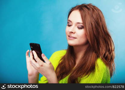 Technology and communication. Happy woman teenage girl texting on mobile phone, using smartphone reading sms message on blue