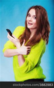 Technology and communication. Woman teenage girl texting on mobile phone, using smartphone reading sms, thumb up hand gesture on blue