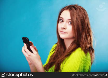 Technology and communication. Woman teenage girl texting on mobile phone, using smartphone reading sms message on blue