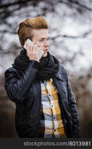 Technology and communication. Young fashion man talking on mobile cell phone using smartphone outdoor