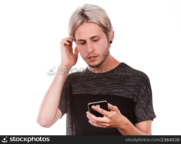 Technology and communication. Young man sad serious face expression using mobile phone reading bad message, isolated on white. Shocked man using mobile phone read message