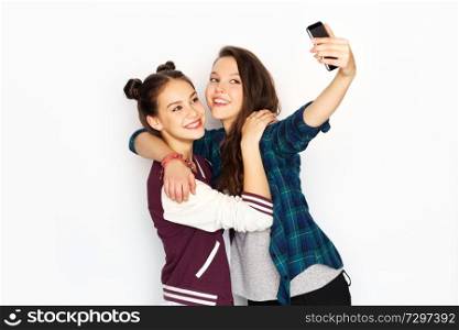 technology and friendship concept - happy smiling pretty teenage girls taking selfie by smartphone over white background. happy teenage girls taking selfie by smartphone
