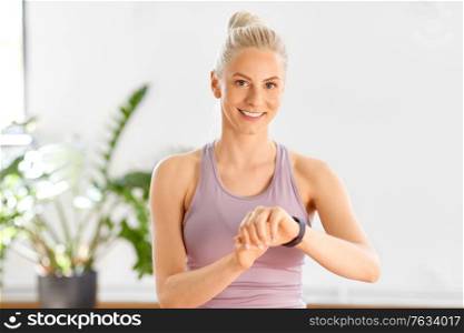 technology and healthy lifestyle concept - happy smiling young woman with fitness tracker at home or yoga studio. woman with fitness tracker home or yoga studio