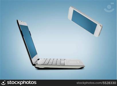 technology and internet concept - smartphone and laptop connecting