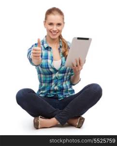 technology and internet concept - smiling young woman in casual clothes sitiing on floor with tablet pc computer and showing thumbs up