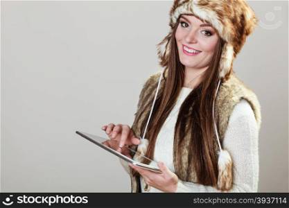 Technology and Internet concept. Young pretty woman in winter clothes holding tablet computer. Studio shot on gray background.