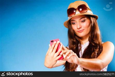 Technology and internet. Happy woman using cellphone texting on mobile phone. Teen girl reading sms on smartphone, taking selfie on blue