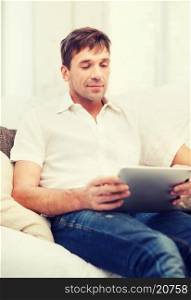 technology and lifestyle concept - handsome man working with tablet pc at home