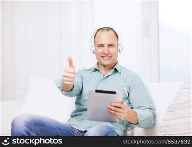 technology and lifestyle, distance learning concept - handsome man with tablet pc computer and headphones at home showing thumbs up